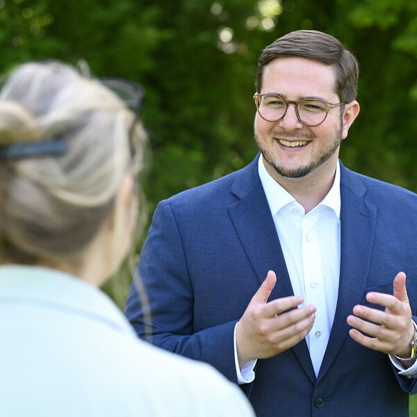 Gilbert Weber im Gespräch mit einer Bürgerin. Er trägt einen blauen Anzug.