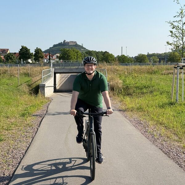 Gilbert Weber auf dem Fahrrad. Im Hintergrund die Burgruine von Staufen im Breisgau