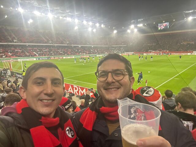 Zwei Fussballfans mit rot-schwarzen Fanschals im Stadion beim Fussballspiel des 1.FC Freiburg e.V.